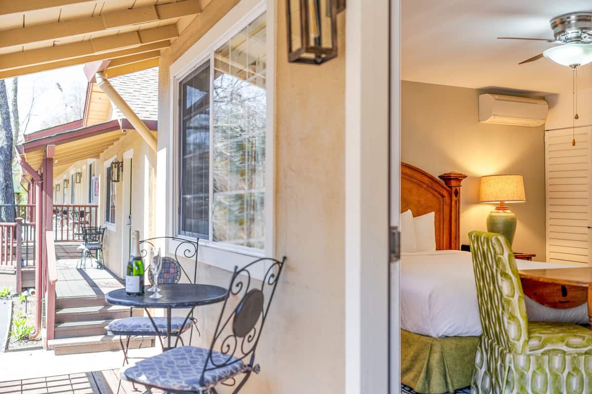 A hotel room with a bed, a nightstand, a lamp, and a chair.