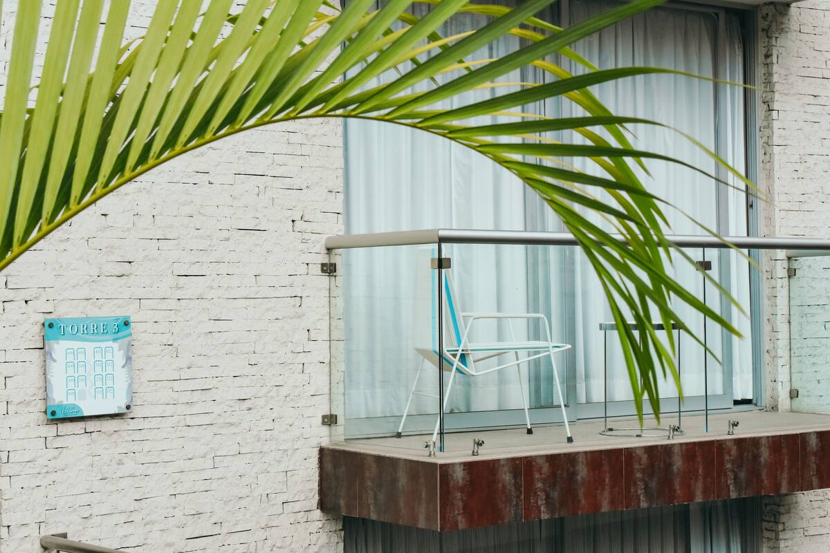 A balcony with a metal railing, a chair, and a sign labeled "TORRE 3".
