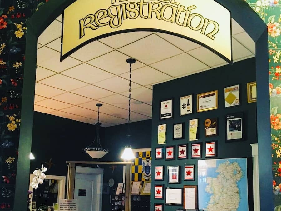 A hotel registration area with a sign above the counter, a map on the wall, and various framed awards or certificates displayed.