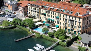 Un hotel de varios pisos con piscina, barcos amarrados y abundante vegetación.