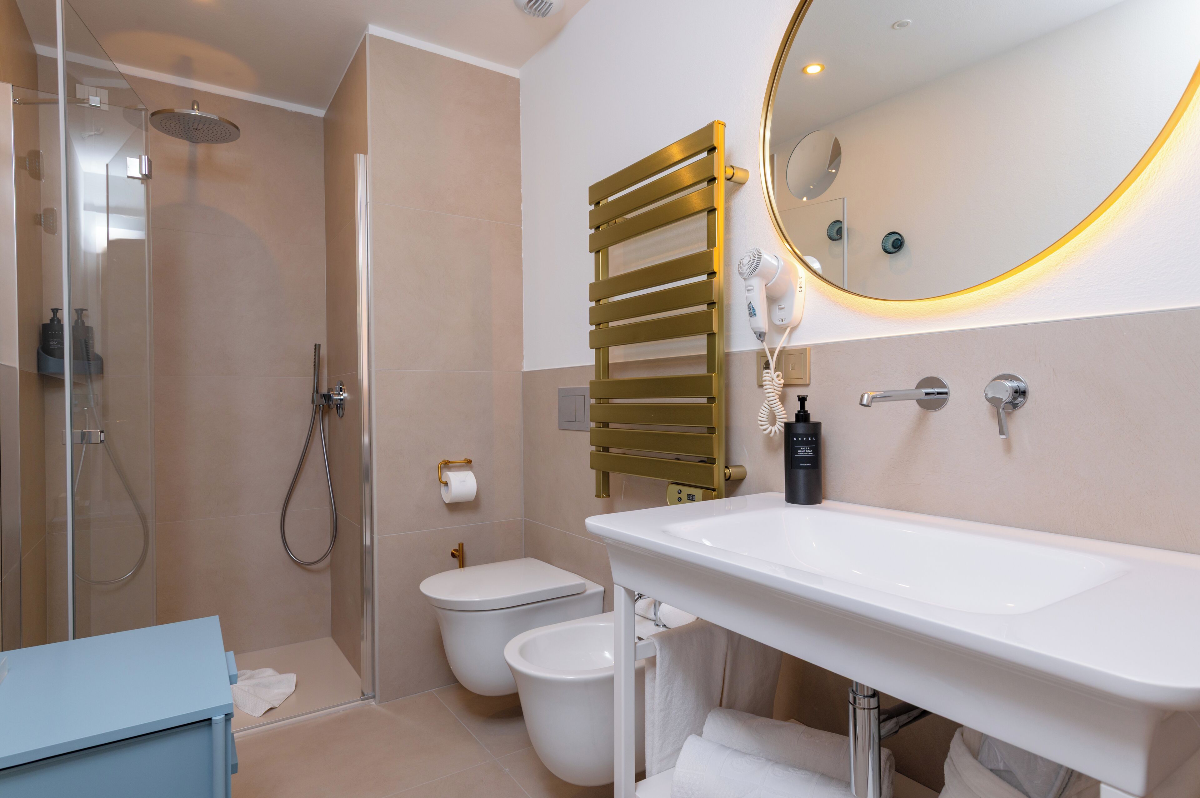 A modern bathroom with a shower, toilet, bidet, and a large sink with a mirror.