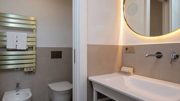 Un bagno con bidet, servizi igienici e lavandino con specchio.