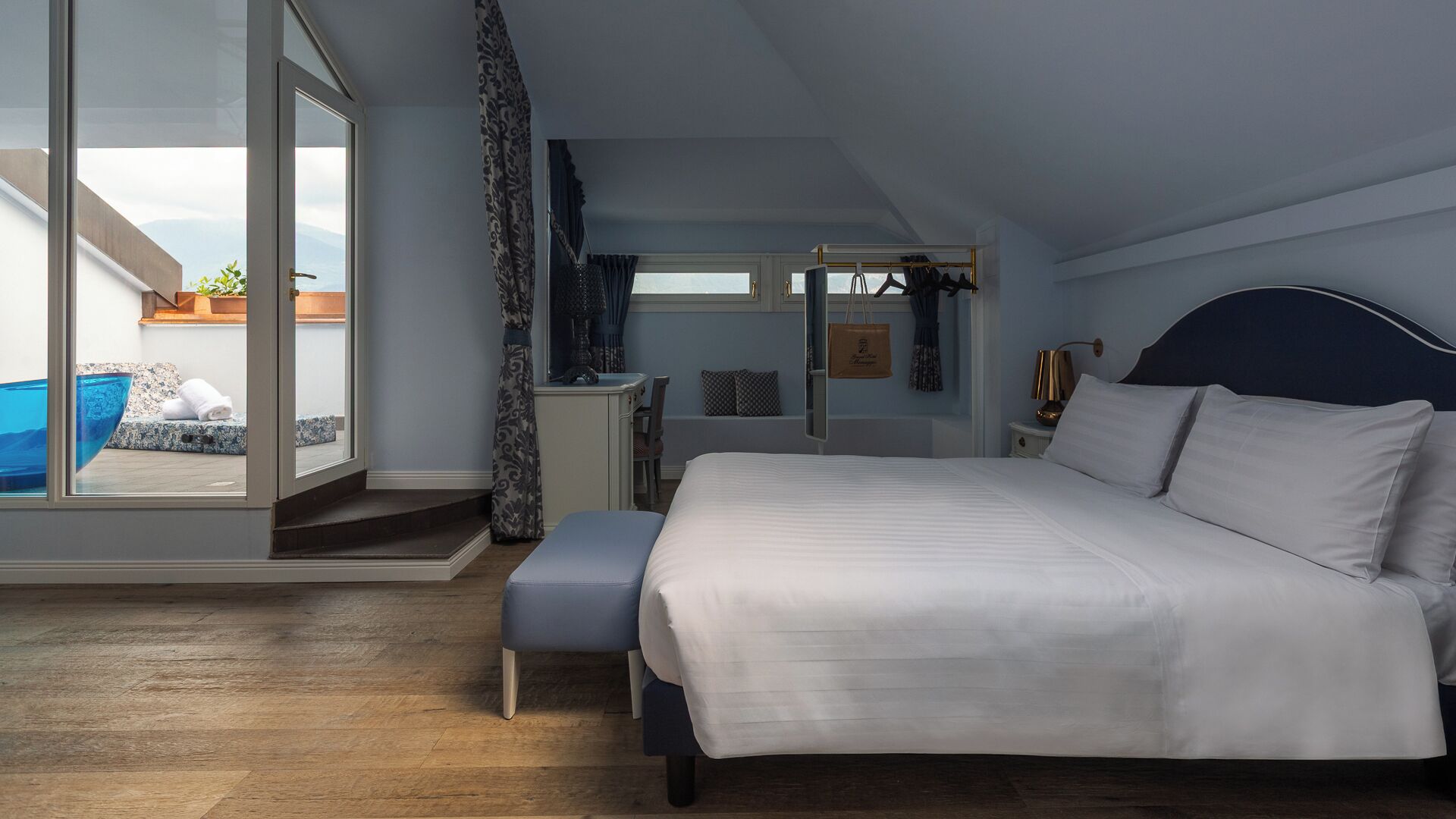 Een slaapkamer met een groot bed, een bureau en uitzicht op een zwembad.