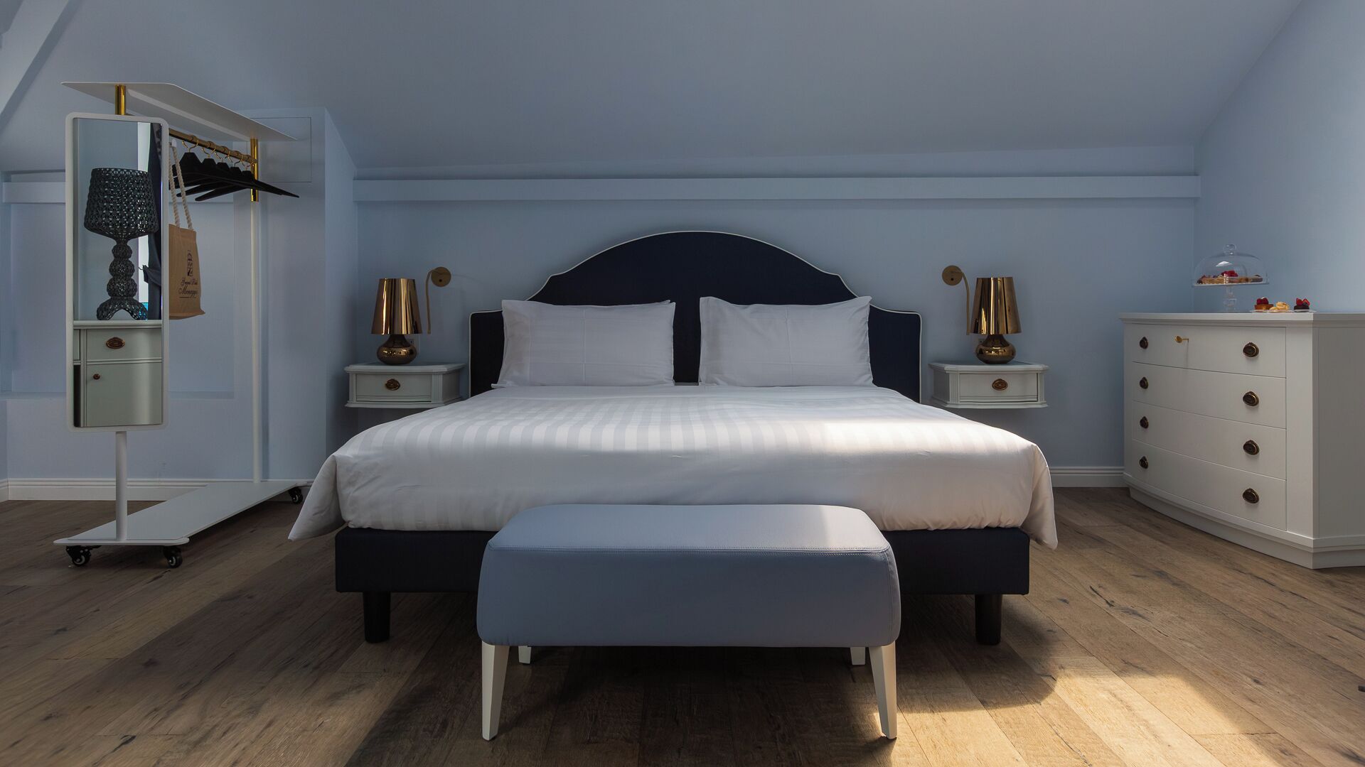 Un dormitorio con una cama grande, mesitas de noche, un aparador y un espejo.