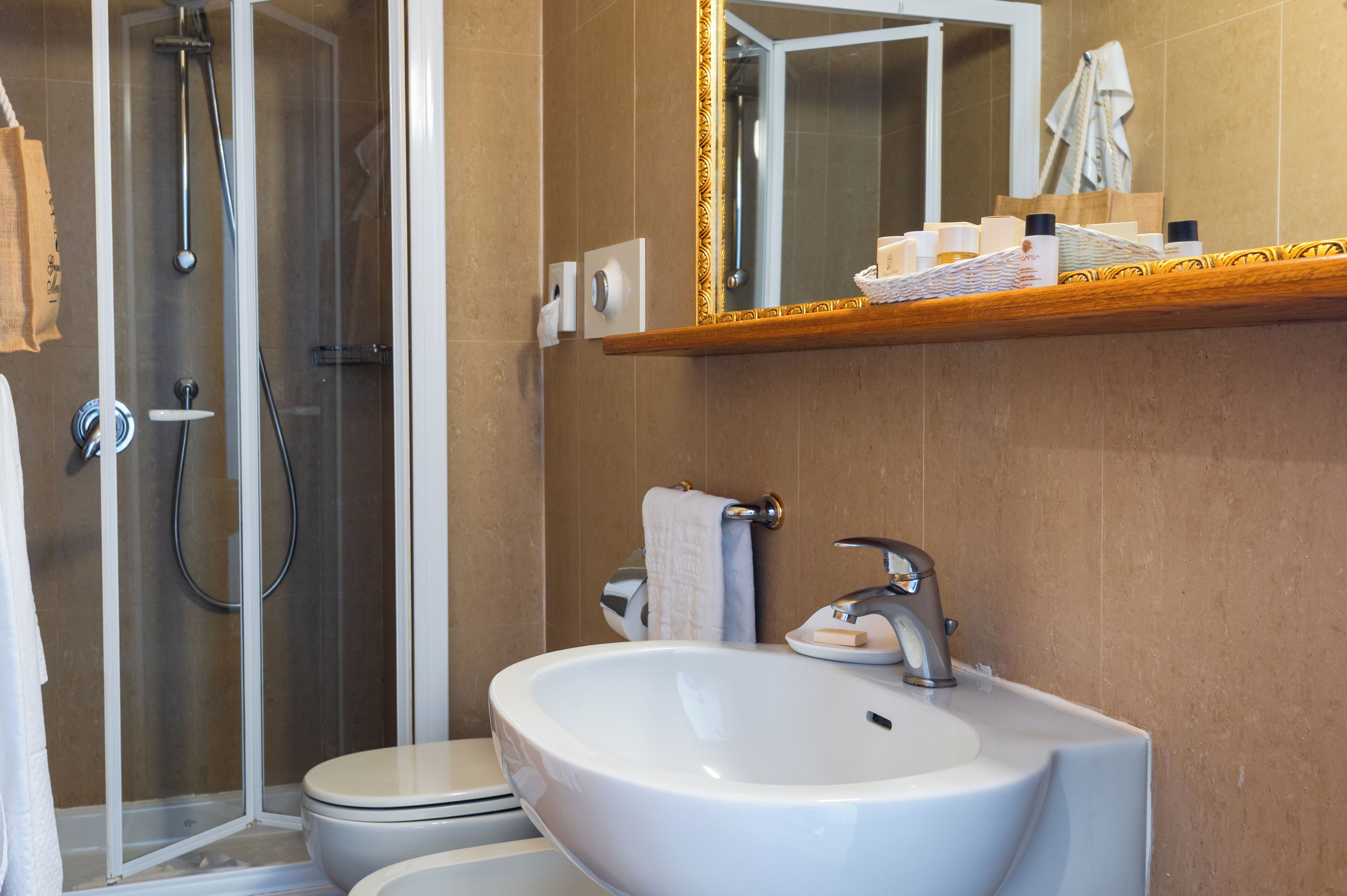 A bathroom with a shower, toilet, sink, and a mirror with a towel rack.