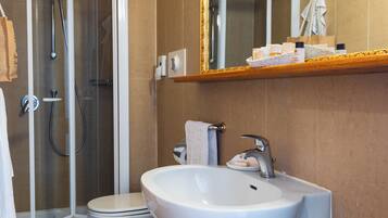 Ein Badezimmer mit Dusche, Toilette, Waschbecken und Spiegel mit Handtuchhalter.