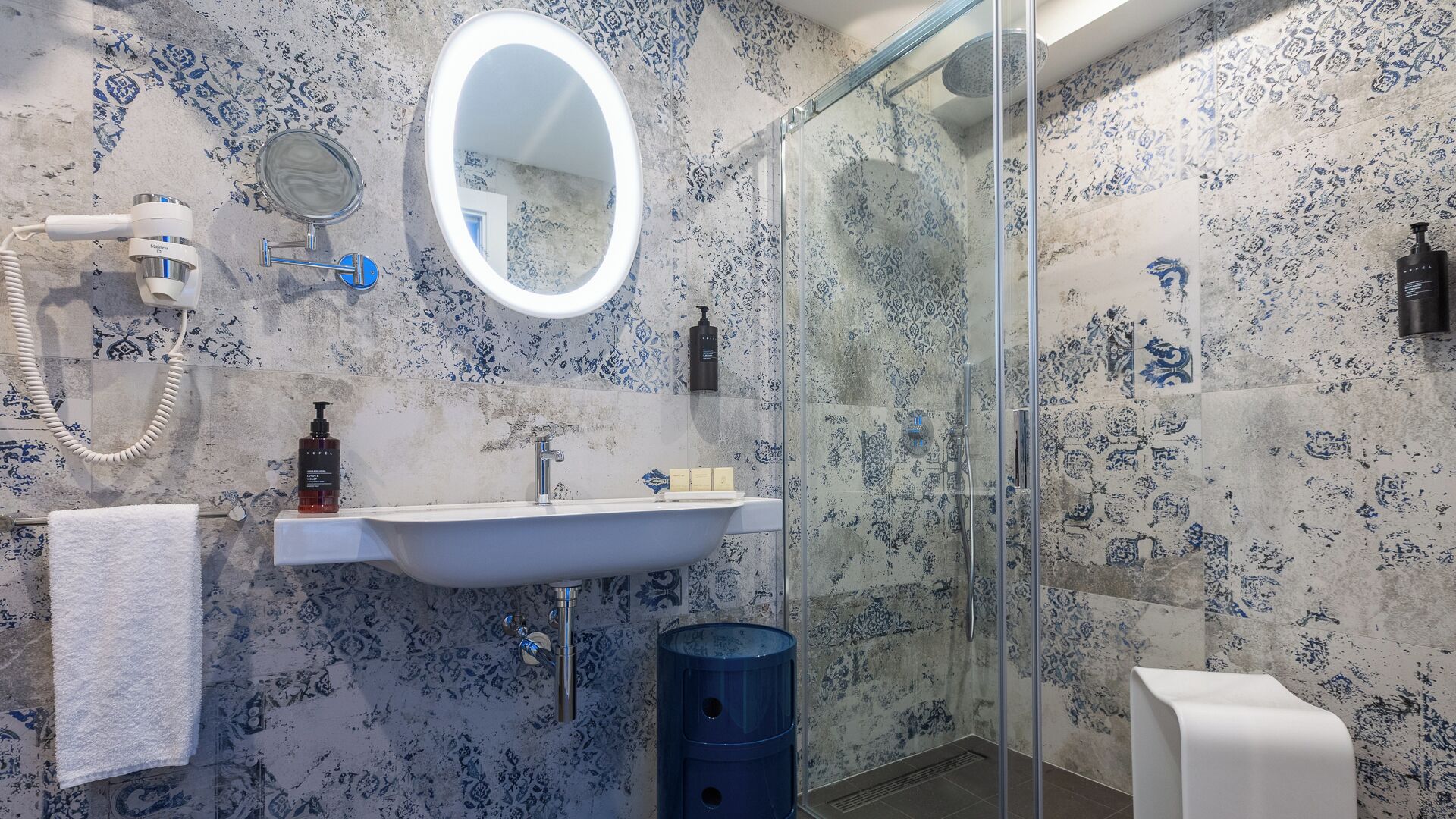 Une salle de bain avec un lavabo blanc, un miroir, une douche et un porte-serviettes.