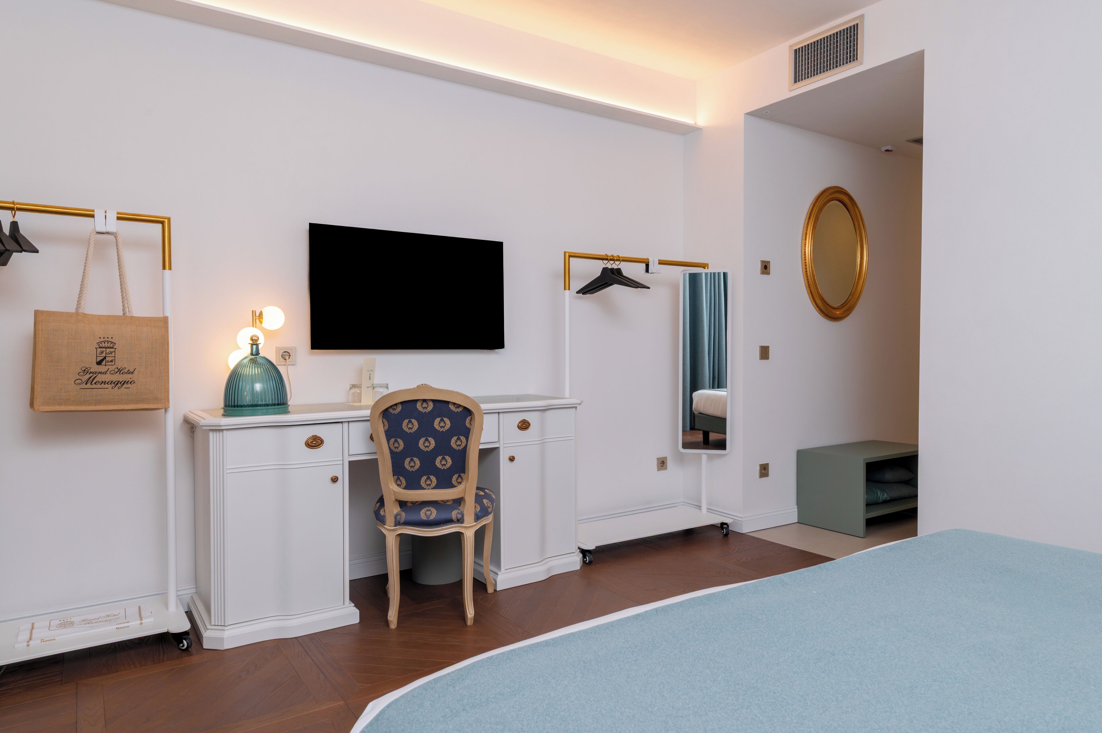 Un dormitorio con una cama, un escritorio con silla, televisor, espejo y armario.
