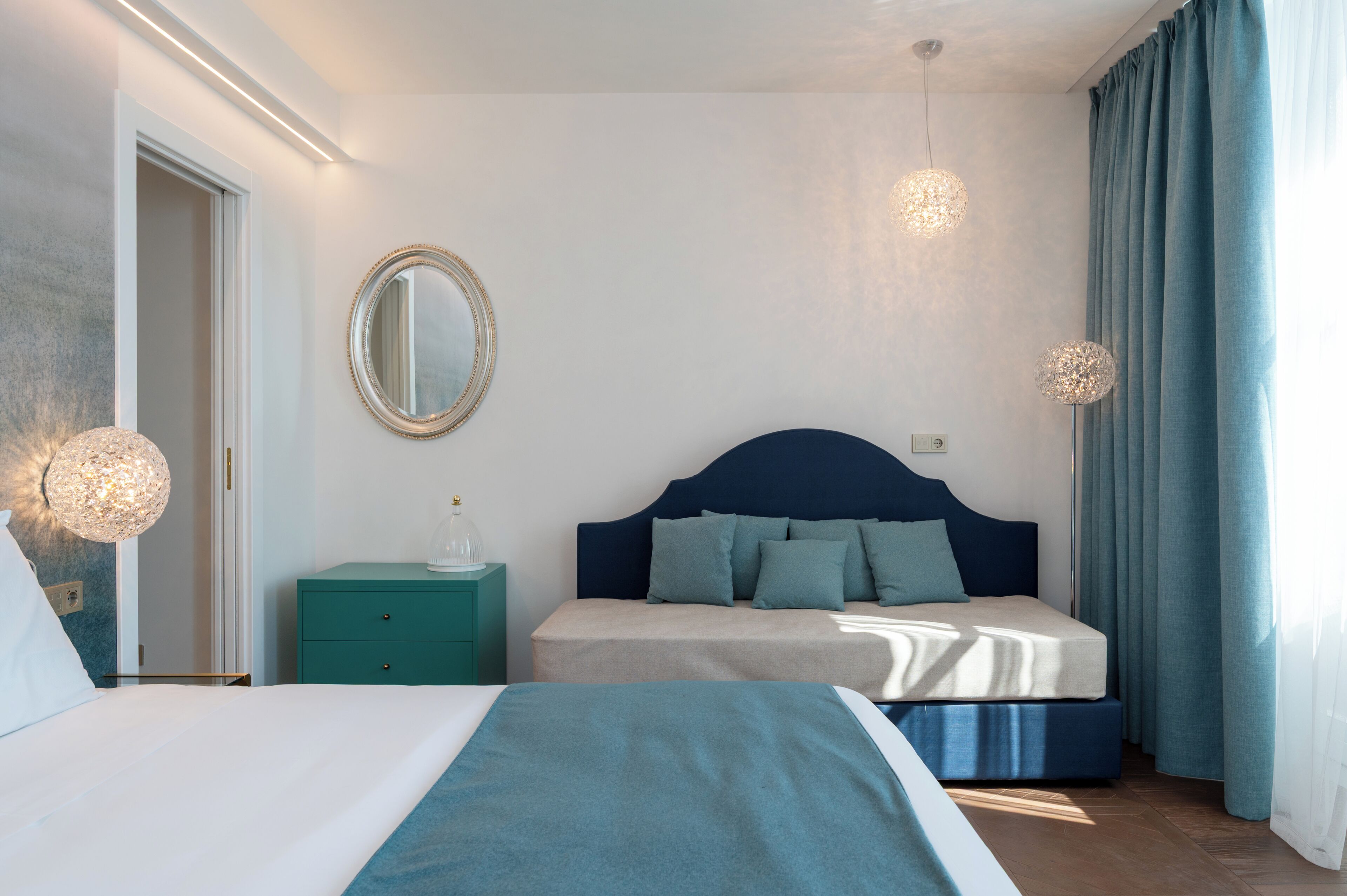 Un dormitorio con cama, mesitas de noche, un espejo y cortinas.