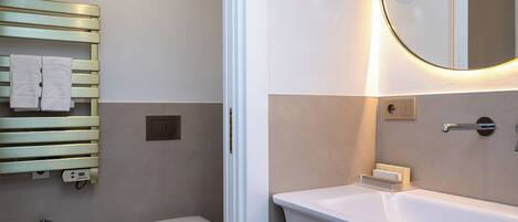 A bathroom with a white sink, a bidet, a toilet, and a towel rack.