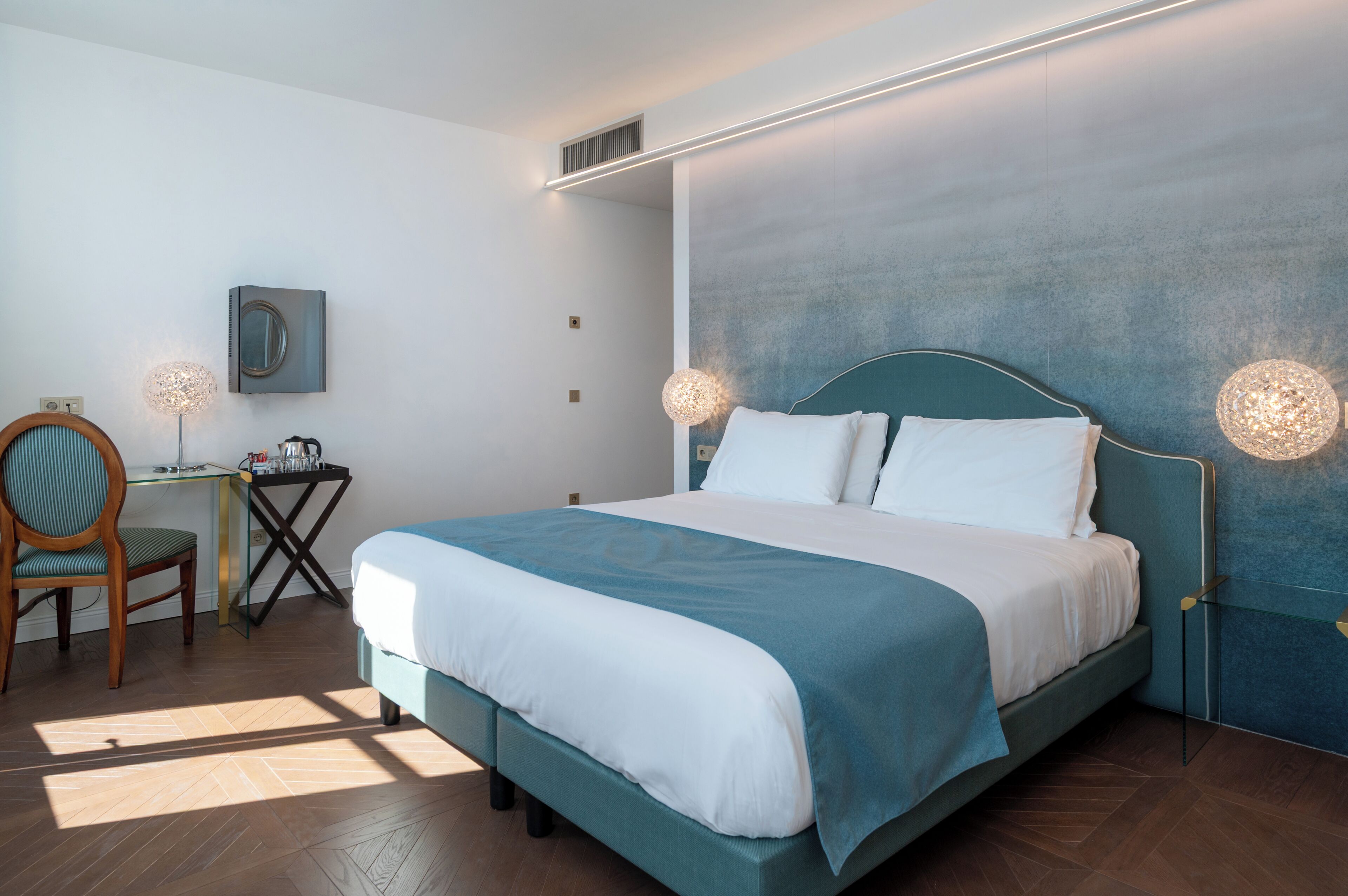Un dormitorio moderno con cama, lámparas de noche, escritorio y una silla.