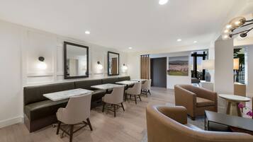 Een moderne hotel lobby met een zithoek, een receptiebalie en uitzicht op het omliggende landschap.