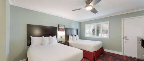 A hotel room with two beds, a ceiling fan, a window with blinds, and a door.