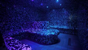A room with a patterned floor and walls, a seating area, and a small pool.