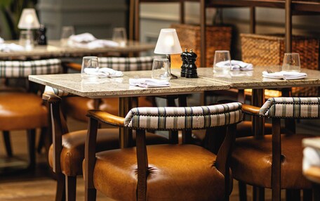 A restaurant interior with wooden tables, leather chairs, and a warm ambiance.