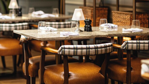 A restaurant interior with wooden tables, leather chairs, and a warm ambiance.