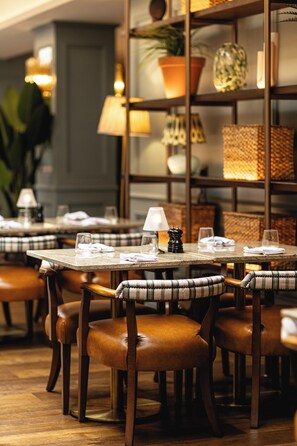 Een restaurantinterieur met houten tafels, lederen stoelen en een warme sfeer.