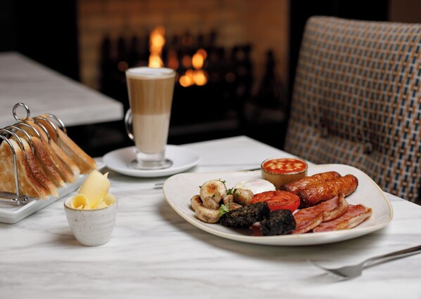 A breakfast setting with toast, a cup of coffee, beans, sausages, mushrooms, and a plate of eggs. - Mount Errigal Hotel Conference & Leisure Centre (Letterkenny)
