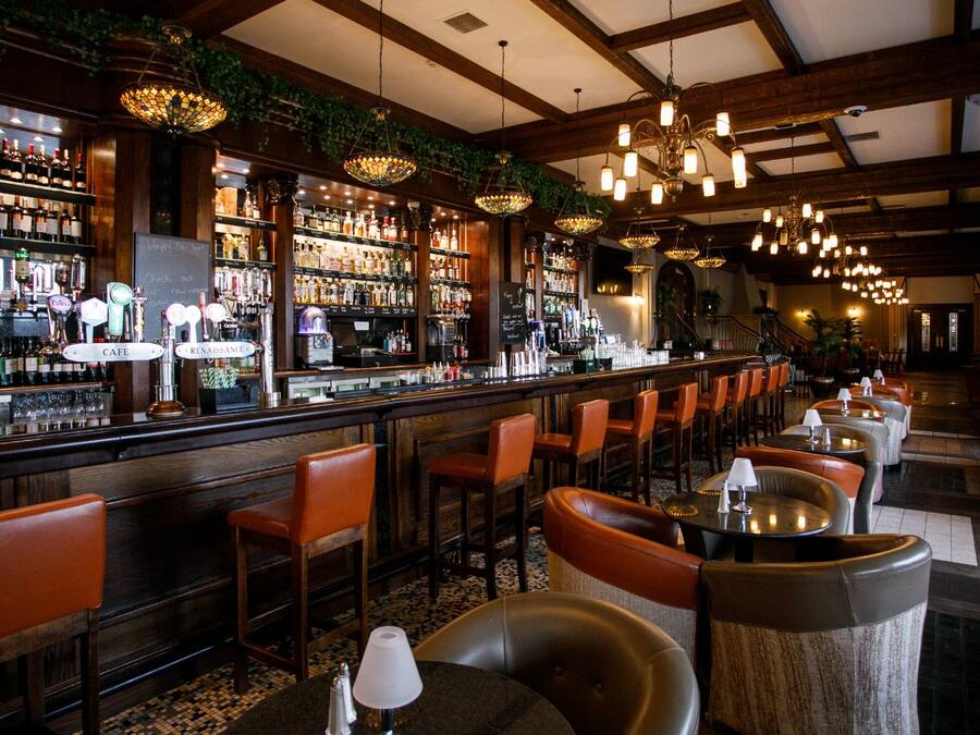 A bar area with multiple seating options, a bar counter, and a variety of bottles.