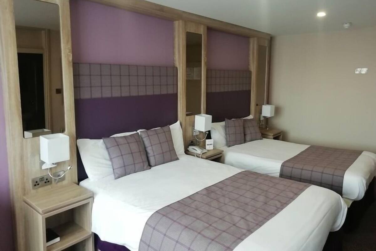 Ein Hotelzimmer mit zwei Betten, jeweils einem Nachttisch, einem Spiegel und einer Lampe.