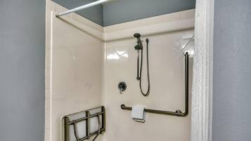 A shower area with a grab bar, a towel rack, and a handheld showerhead.