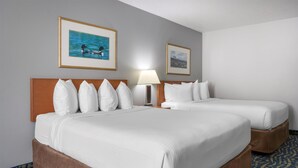 A hotel room with two beds, a headboard, a lamp, and two framed pictures on the wall. - SureStay Plus Hotel by Best Western Lethbridge (Lethbridge)