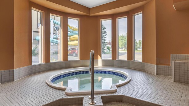A hot tub in a corner with a view of a water slide and a parking lot. - SureStay Plus Hotel by Best Western Lethbridge (Lethbridge)