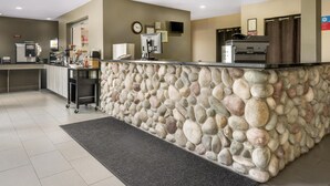 A reception area with a stone counter, a clock, a television, and a coffee machine. - SureStay Plus Hotel by Best Western Lethbridge (Lethbridge)