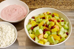 Eine Schüssel Obstsalat mit verschiedenen Früchten und eine Schüssel Quark.