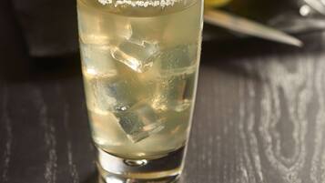 A glass of a clear beverage with ice cubes and a lime slice, on a dark wooden table.