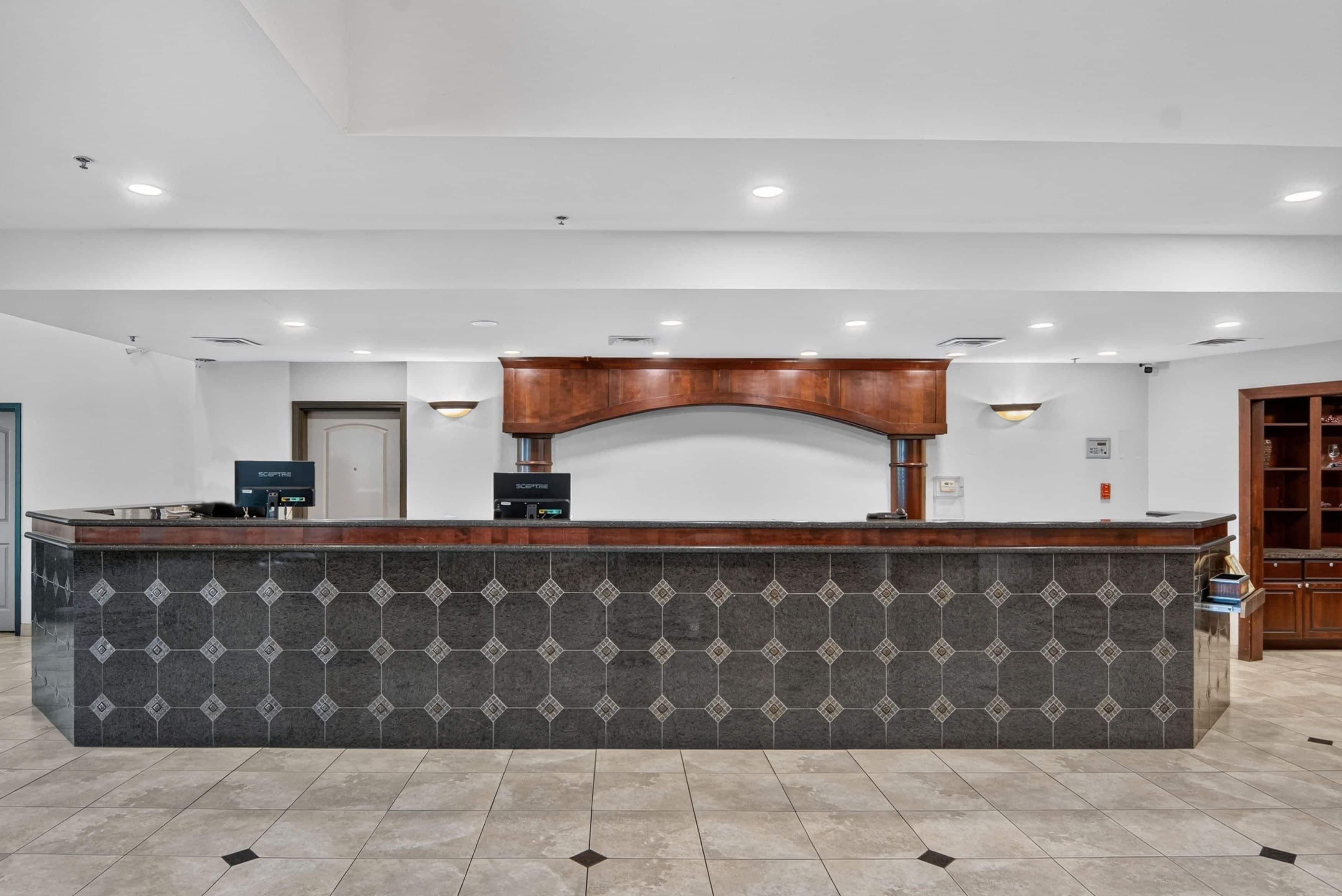A reception desk with a patterned tile design, a wooden counter, and a modern light fixture.