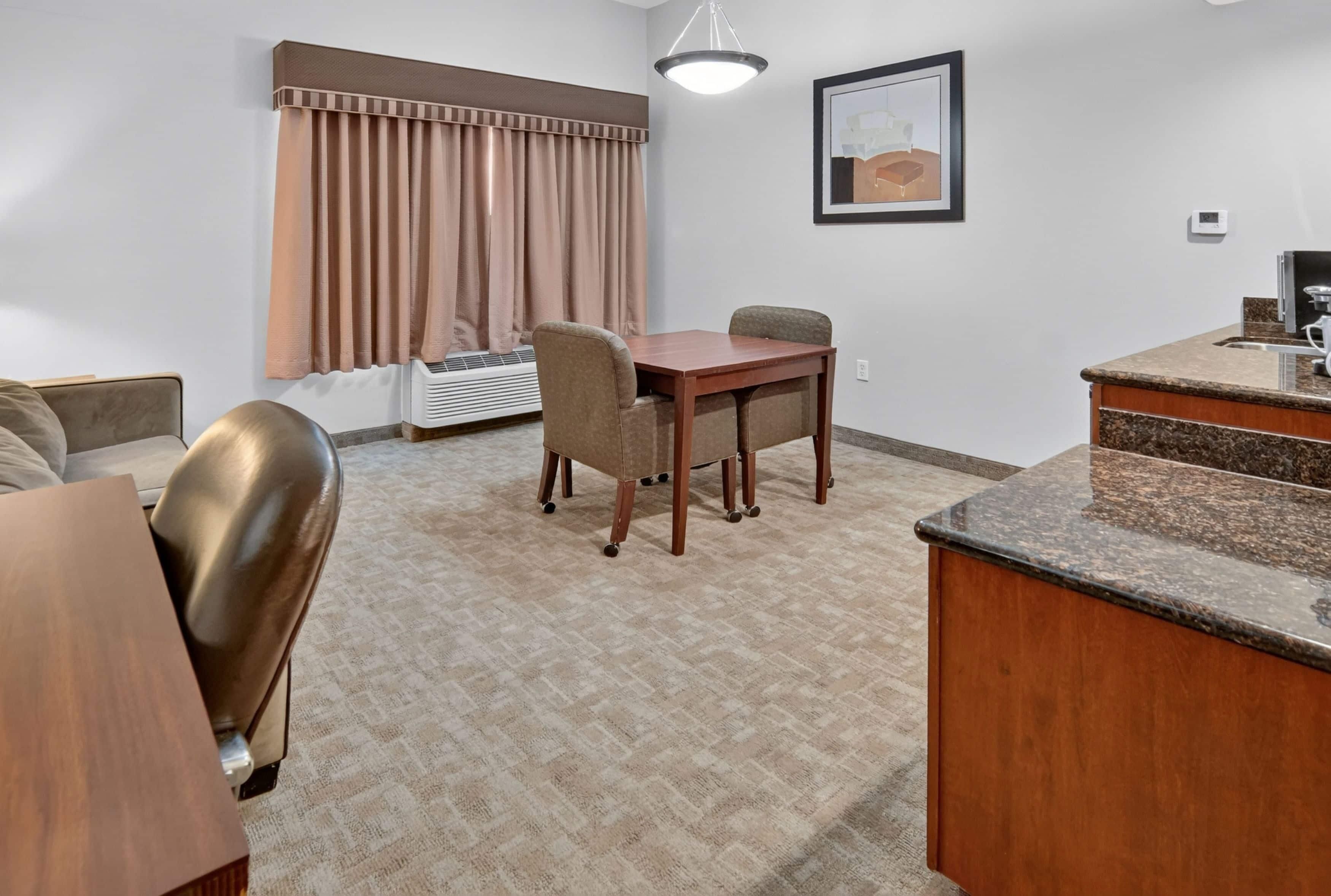A compact living space with a dining table, a sofa, a kitchenette, and a window with curtains.