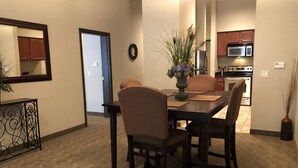A dining area with a dark wooden table and four chairs, a vase with flowers, and a mirror on the wall. - Hawthorn Extended Stay by Wyndham Killeen (Killeen)
