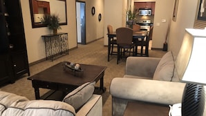 A living room with a sofa, a coffee table, and a lamp. There is a dining area with chairs and a table in the background. - Hawthorn Extended Stay by Wyndham Killeen (Killeen)