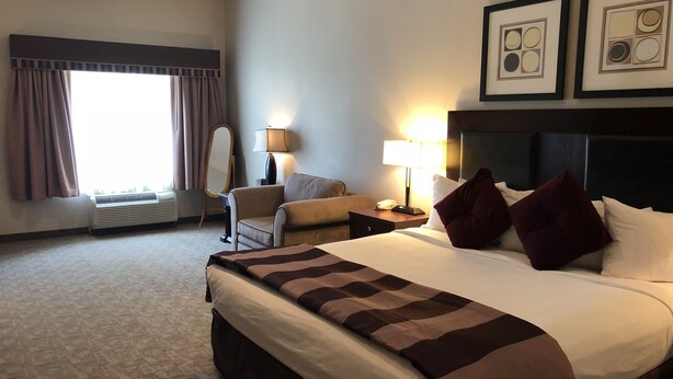 A hotel room with a large bed, a chair, a desk with a lamp, and a window with curtains. - Hawthorn Extended Stay by Wyndham Killeen (Killeen)