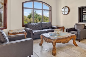 A living room with a leather sofa, two armchairs, a glass-top coffee table, and a decorative wooden side table. - Hawthorn Extended Stay by Wyndham Killeen (Killeen)