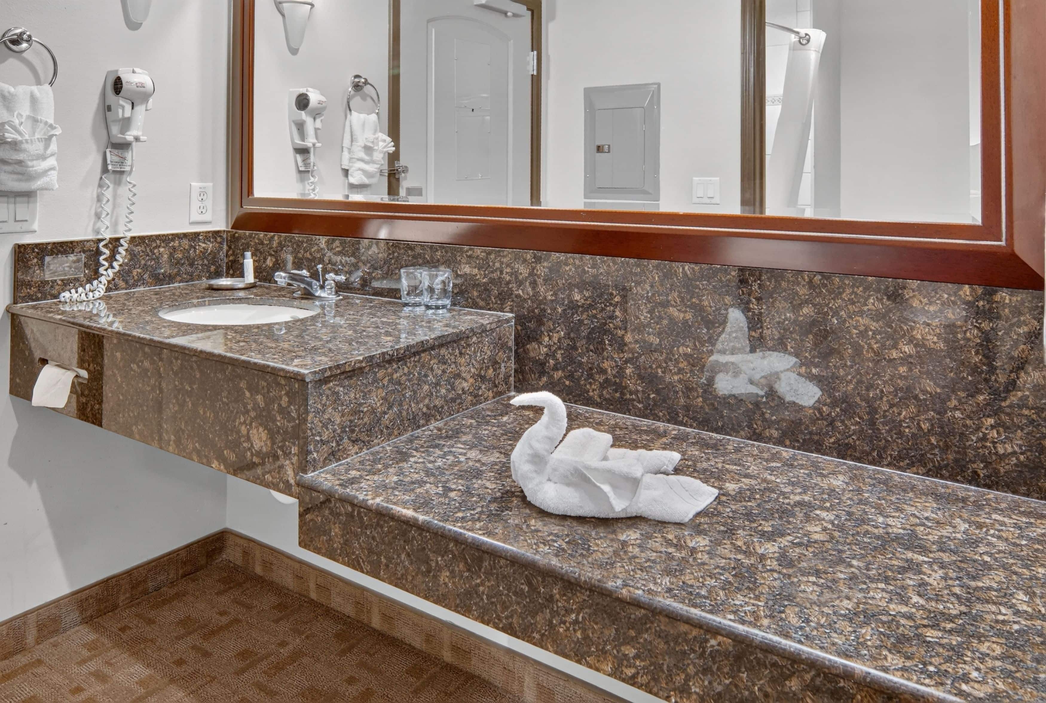 A bathroom with a marble sink, a mirror, and a towel rack.
