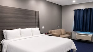 Une chambre d’hôtel avec un grand lit, un canapé, un bureau et une fenêtre avec des rideaux.
