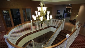 A grand, circular staircase with white balustrades and a chandelier in the center. - Town & Country Inn and Suites (Quincy)