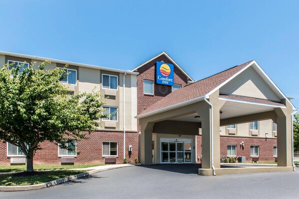 A Comfort Inn hotel with a brick facade, a covered entrance, and a clear sky.