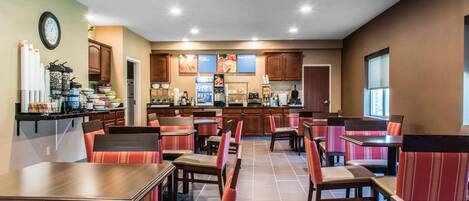 A restaurant with booths and tables, a kitchen area, and a clock on the wall.