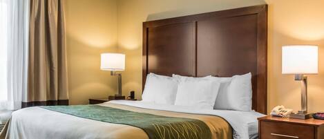 A hotel room with a bed, two bedside lamps, a nightstand with a phone, and a window with curtains.