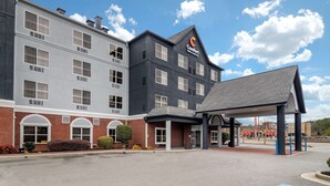 Een hotel met een modern design, met een combinatie van baksteen en een donkere gevel, grote ramen en een overdekt entreegebied.