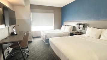Een hotelkamer met twee bedden, een bureau, een stoel, een telefoon en een raam.