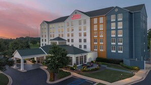 Un Hilton Garden Inn de diseño moderno, con un amplio estacionamiento y un área exterior bien cuidada con asientos.