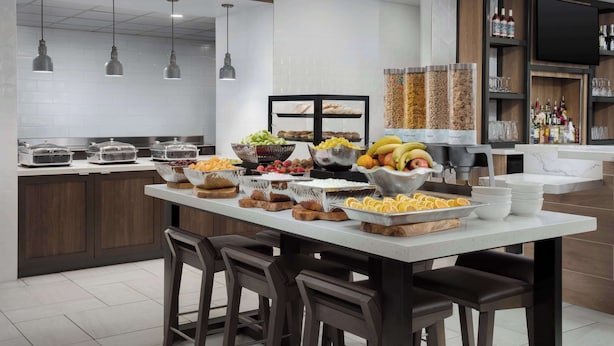 Una cocina moderna con una isla central, zona de bar y diversas opciones de comida y bebida.