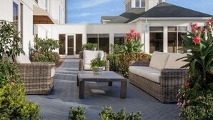 Un patio exterior con mobiliario de mimbre, una mesa de centro y plantas en macetas.