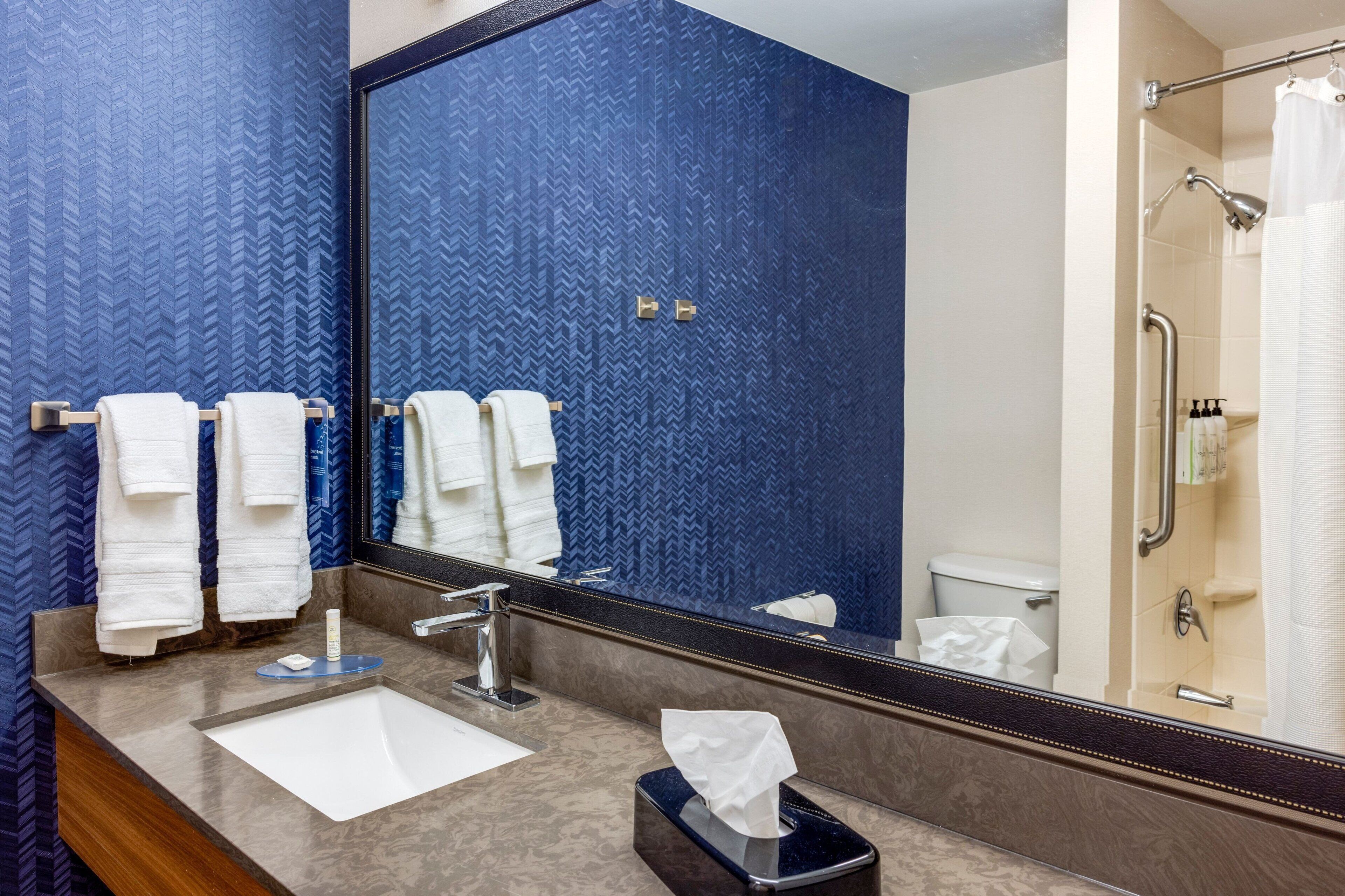 A bathroom with a large mirror, a sink, and a shower area.