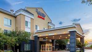 Entrada de un hotel Fairfield Inn & Suites by Marriott, con un paseo techado y un área de acceso ajardinada.