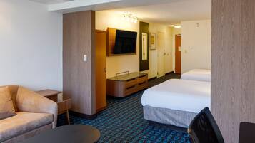 A hotel room with a sofa, a small table, a TV, a mirror, a dresser, and a bed.
